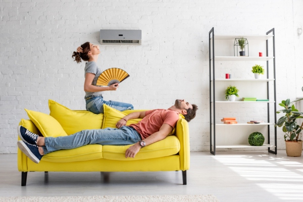 couple lounging in front of AC but still feeling warm depicting diminished performance