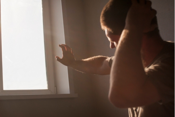 man feeling extreme heat from the sun cutting through the window