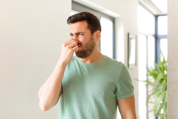 man covering nose due to bad smell from air conditioner