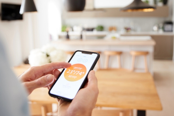homeowner adjusting thermostat using mobile phone depicting set back thermostat
