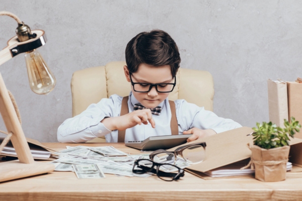 Kid using calculator with dollar bills on the table depicting HVAC load calculation