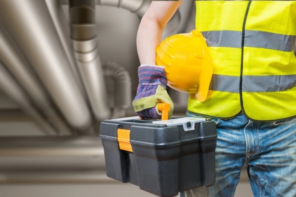 cropped view of worker with tools with ductwork behind him depicting damaged HVAC ductwork