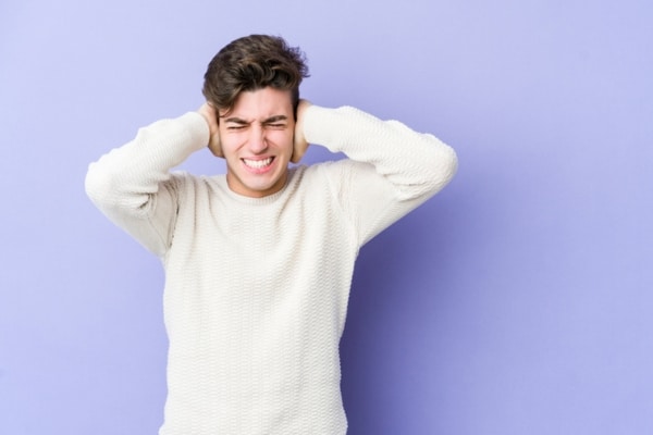 man covering ears due to furnace sounds