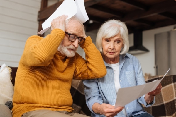 senior couple on the couch shocked with expensive energy costs due to short cycling furnace