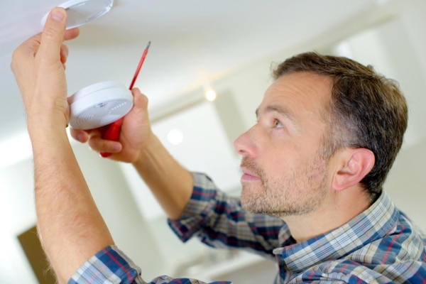 homeowner installing a carbon monoxide detector at home