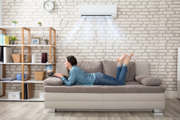 woman keeping warm and cozy while using laptop in the living room with ductless mini-split installed