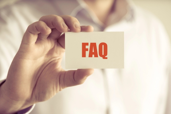 cropped view of a man holding a card that says FAQ depicting questions about furnace