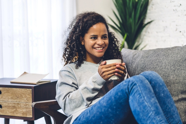 woman holding a cup of coffee while lounging on the couch and enjoying good indoor air quality