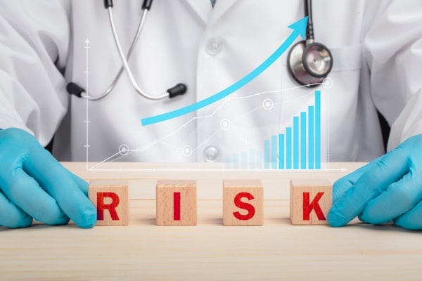 A doctor and wooden letter blocks spelling risk depicting health risk