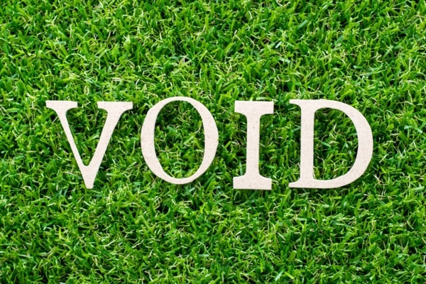 Wood letter in word void on artificial green grass background depicting invalid warranty