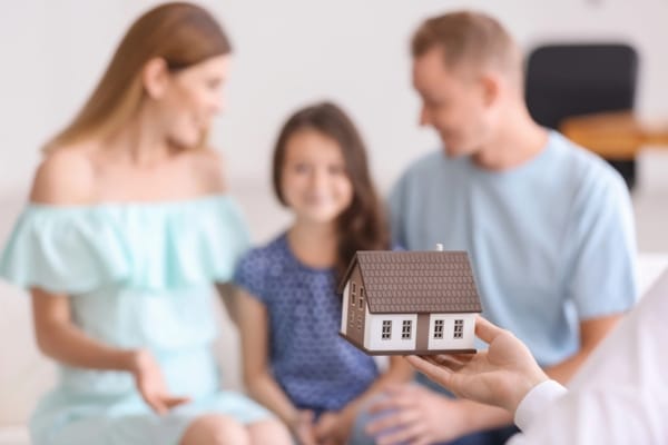 blurred family in the background with a miniature house in the foreground depicting assessing air filtration needs