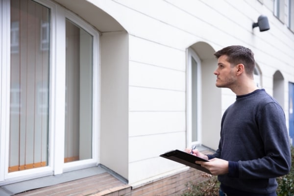 homeowner holding a pen and clipboard assessing heat loss at home